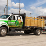 A truck with a green and white trailer on the back.