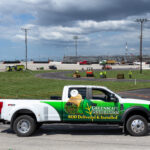 A truck with a green and white wrap parked on the side of a road.