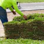 A man in an orange shirt is putting grass into a pile