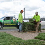 Two men in green shirts and a truck