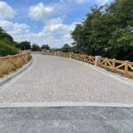 A road with a wooden fence and trees in the background.