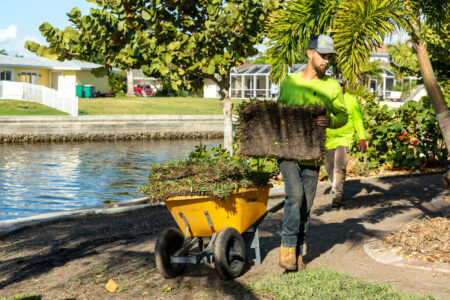 A man pushing a cart full of plants.